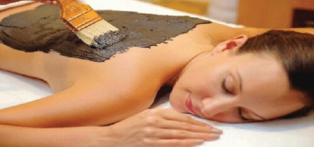 A spa client wrapped in a soothing body wrap, relaxing on a treatment bed, with warm towels and spa ambiance enhancing the experience.